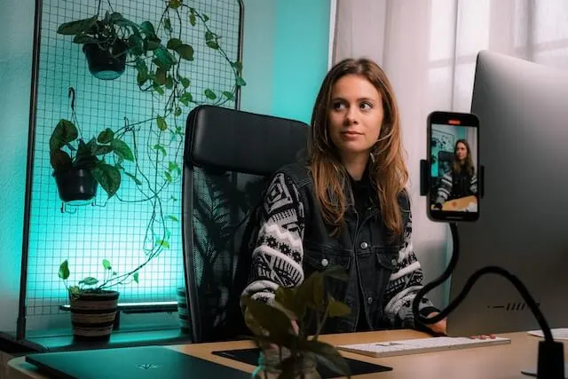 A YouTuber at her desk shooting a video with her phone.